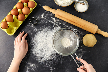 Image showing hands with strainer sifting flour on kitchen table