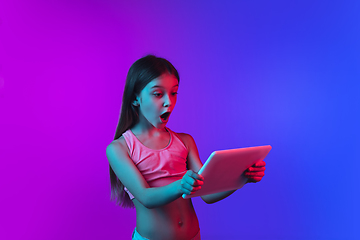 Image showing Little caucasian girl\'s portrait isolated on gradient pink-blue background in neon light.