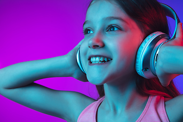 Image showing Little caucasian girl\'s portrait isolated on gradient pink-blue background in neon light.