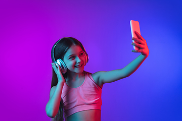 Image showing Little caucasian girl\'s portrait isolated on gradient pink-blue background in neon light.