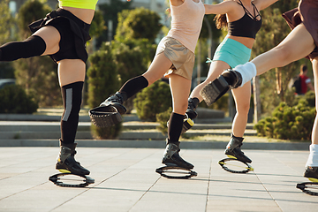 Image showing Beautiful women in sportswear jumping in a kangoo jumps shoes at the street on summer\'s sunny day