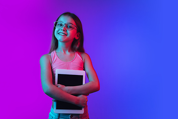 Image showing Little caucasian girl\'s portrait isolated on gradient pink-blue background in neon light.