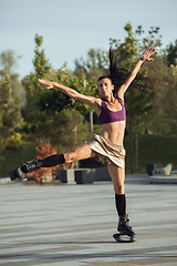 Image showing Beautiful woman in sportswear jumping in a kangoo jumps shoes at the street on summer\'s sunny day