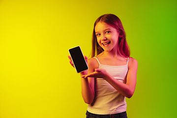 Image showing Little caucasian girl\'s portrait isolated on gradient background in neon light. Concept of human emotions, facial expression, modern gadgets and technologies. Copyspace.