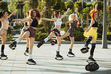 Image showing Beautiful women in sportswear jumping in a kangoo jumps shoes at the street on summer\'s sunny day