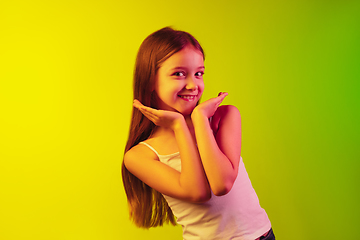 Image showing Little caucasian girl\'s portrait isolated on gradient background in neon light. Concept of human emotions, facial expression, modern gadgets and technologies. Copyspace.