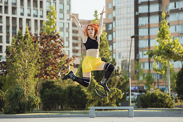 Image showing Beautiful woman in sportswear jumping in a kangoo jumps shoes at the street on summer\'s sunny day