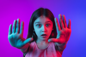 Image showing Little caucasian girl\'s portrait isolated on gradient pink-blue background in neon light.