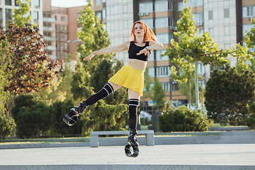 Image showing Beautiful woman in sportswear jumping in a kangoo jumps shoes at the street on summer\'s sunny day