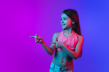 Image showing Little caucasian girl\'s portrait isolated on gradient pink-blue background in neon light.