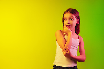 Image showing Little caucasian girl\'s portrait isolated on gradient background in neon light. Concept of human emotions, facial expression, modern gadgets and technologies. Copyspace.