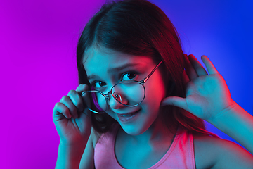 Image showing Little caucasian girl\'s portrait isolated on gradient pink-blue background in neon light.