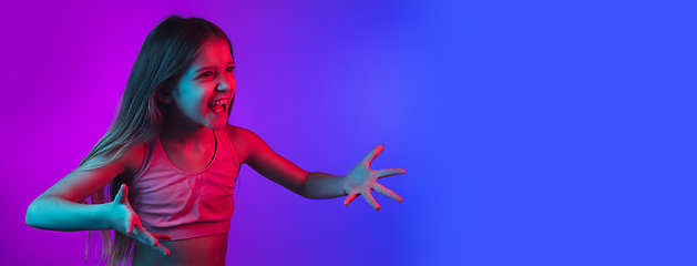 Image showing Little caucasian girl\'s portrait isolated on gradient pink-blue background in neon light.