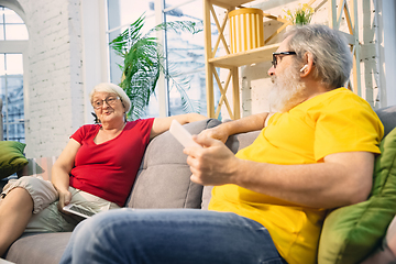 Image showing Couple of seniors spending time together being quarantined - caucasians mature and retired man and woman using modern gadgets, talking, drinking tea