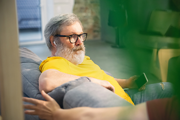 Image showing Couple of seniors spending time together being quarantined - caucasians mature and retired man and woman using modern gadgets, talking, drinking tea