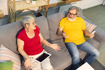 Image showing Couple of seniors spending time together being quarantined - caucasians mature and retired man and woman using modern gadgets, talking, drinking tea