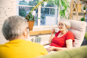 Image showing Couple of seniors spending time together being quarantined - caucasians mature and retired man and woman using modern gadgets, talking, drinking tea