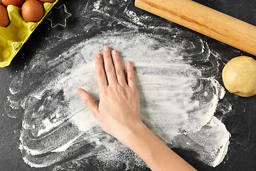 Image showing hand with flour, dough and rolling pin on table