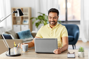 Image showing man with laptop drinking coffee at home office