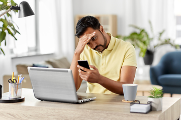 Image showing happy indian man with smartphone at home office