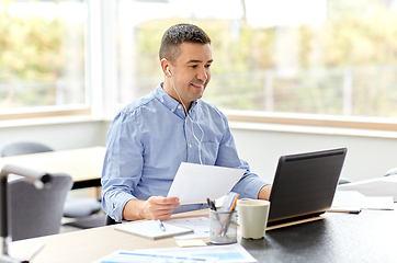 Image showing man in earphones with laptop working at home