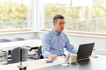 Image showing man with calculator and papers working at home