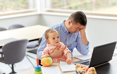 Image showing father with baby working on laptop at home office