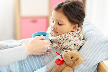 Image showing mother giving hot tea to sick little daughter