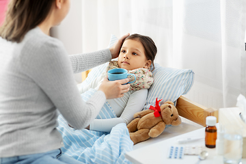 Image showing mother giving hot tea to sick little daughter