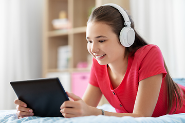 Image showing girl in headphones listening to music on tablet pc