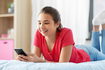 Image showing smiling teenage girl texting on smartphone at home