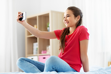 Image showing happy girl with smartphone taking selfie at home