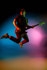 Image showing Young caucasian musician playing on gradient background in neon light. Concept of music, hobby, festival