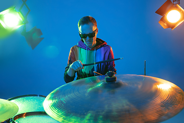 Image showing Young caucasian musician playing on gradient background in neon light. Concept of music, hobby, festival