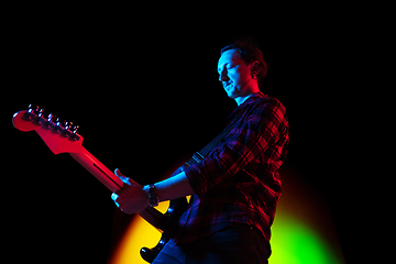 Image showing Young caucasian musician playing on gradient background in neon light. Concept of music, hobby, festival