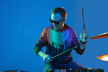 Image showing Young caucasian musician playing on gradient background in neon light. Concept of music, hobby, festival