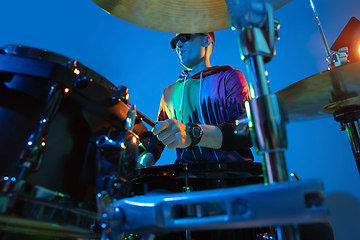 Image showing Young caucasian musician playing on gradient background in neon light. Concept of music, hobby, festival