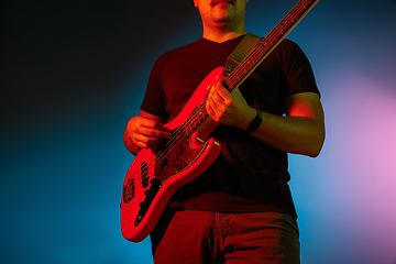 Image showing Young caucasian musician playing on gradient background in neon light. Concept of music, hobby, festival