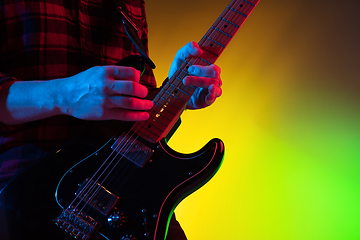 Image showing Young caucasian musician playing on gradient background in neon light. Concept of music, hobby, festival