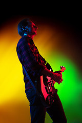 Image showing Young caucasian musician playing on gradient background in neon light. Concept of music, hobby, festival