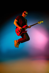 Image showing Young caucasian musician playing on gradient background in neon light. Concept of music, hobby, festival