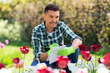 Image showing man with notebook and flowers at summer garden