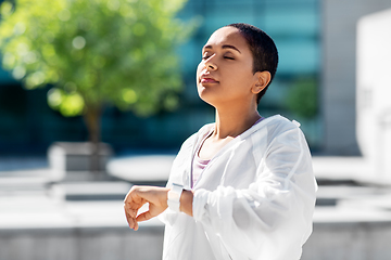 Image showing young woman with smart watch breathing outdoors