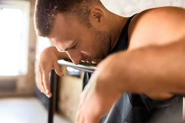 Image showing close up of tired man at parallel bars in gym