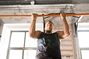 Image showing man exercising on bar and doing pull-ups in gym