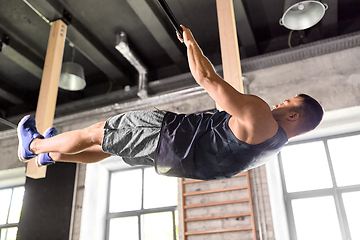 Image showing young man exercising on horizontal bar in gym