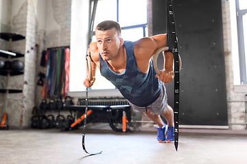 Image showing man doing push-ups on gymnastic rings in gym