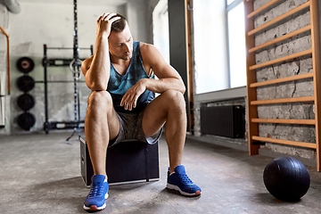 Image showing tired young man with medicine ball in gym