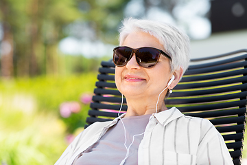 Image showing happy senior woman with earphones at garden