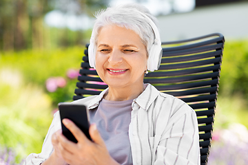 Image showing old woman with headphones and smartphone at garden